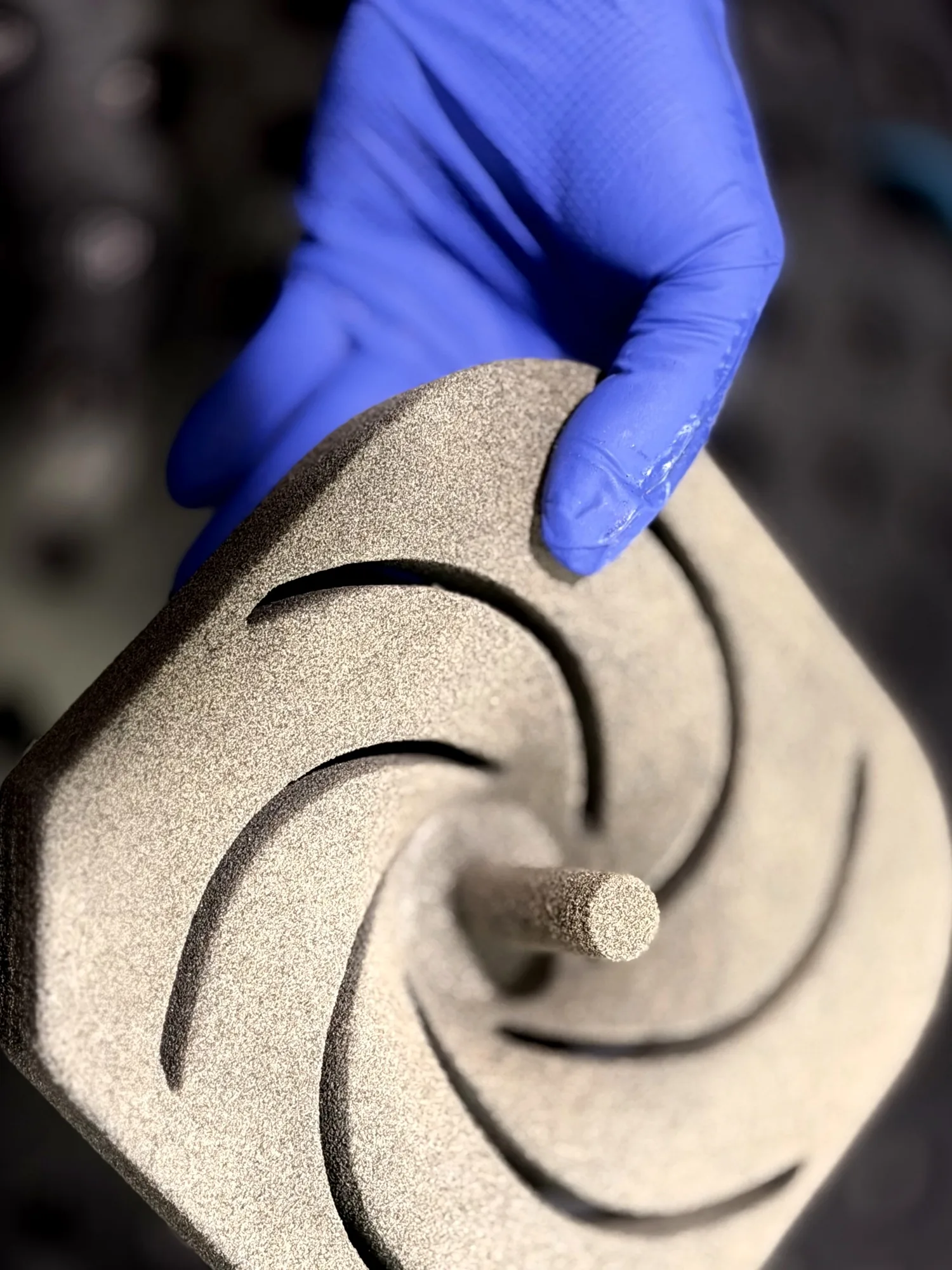 Technician holding a complex 3D-printed sand core