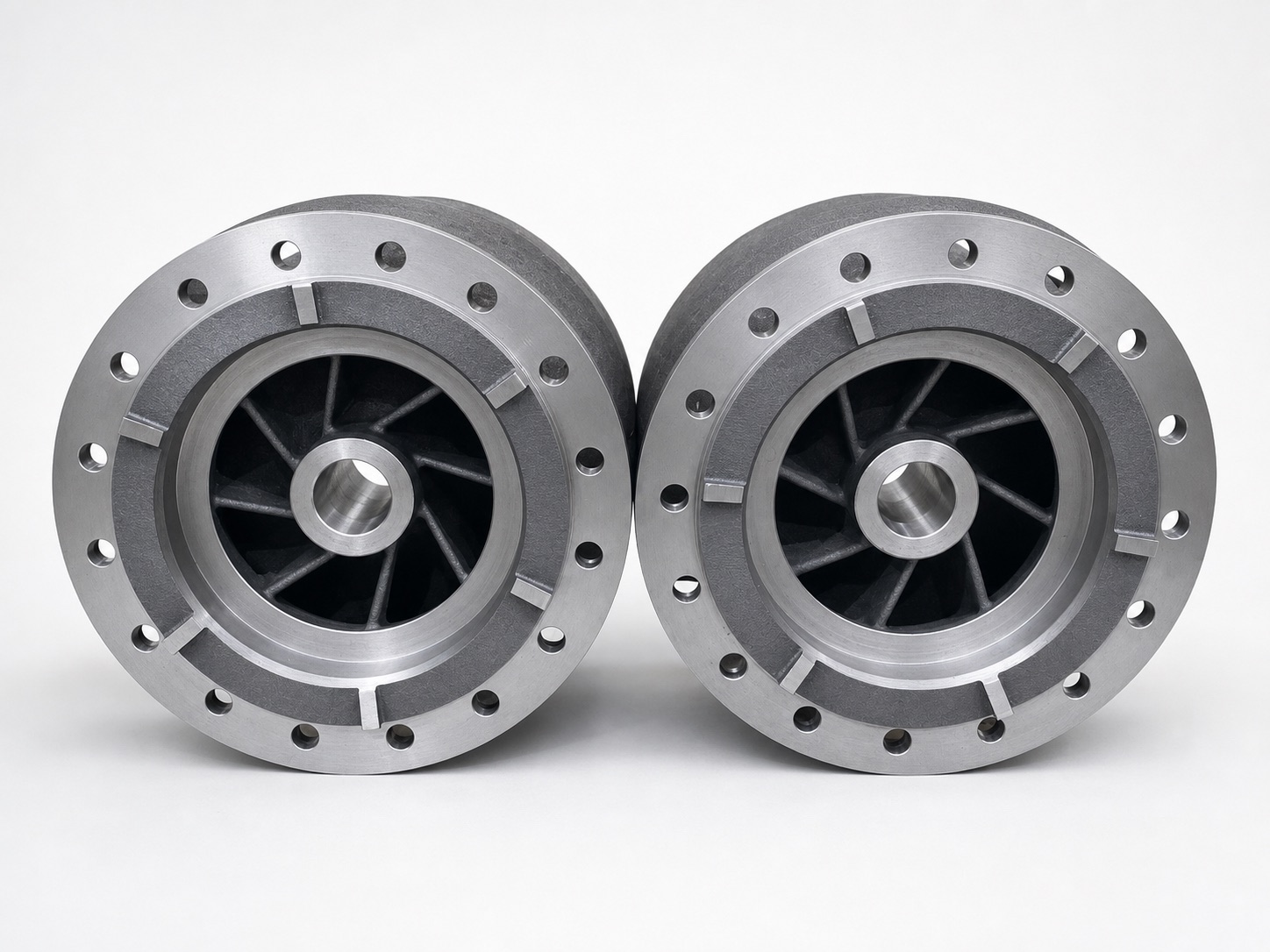 Two finished machined steel pump bowls with flange bolt holes, viewed from the front