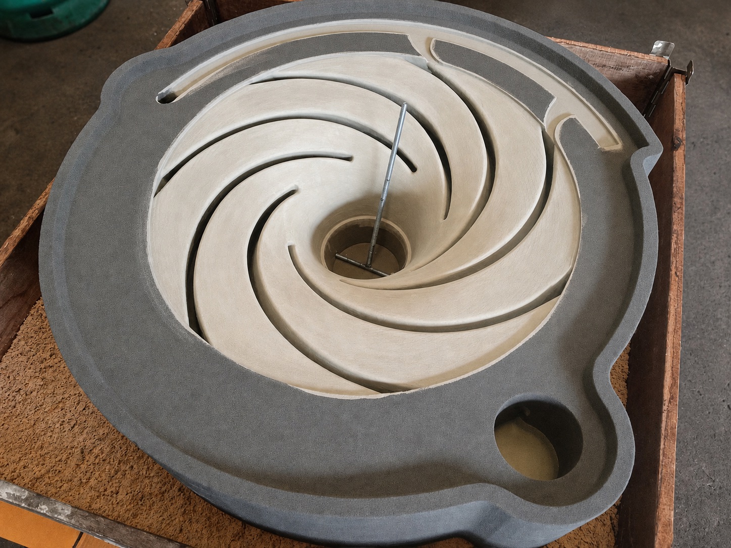 Circular printed sand core seated inside a larger gray sand mold section